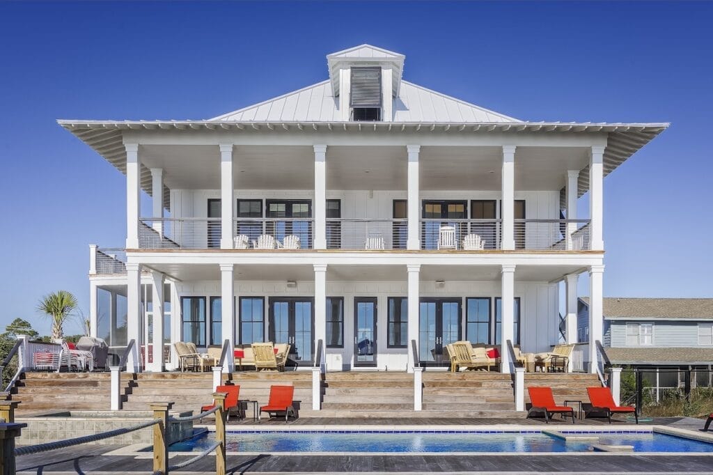 A luxurious-looking two-story white home with a beautiful pool.